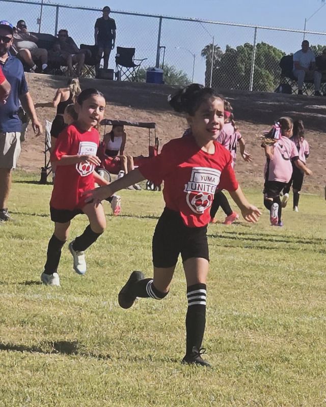 Two Yuma United players running across the field on game day.